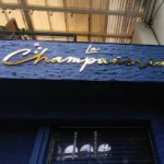 Aviso en acrílico tipo corporeo con acabado dorado instalado en fachada comercial del negocio La Champañería por Idex Publicidad en Medellín.